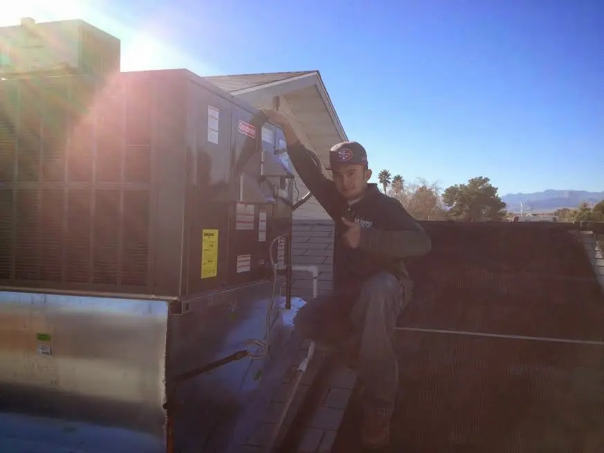 HVAC technician performing AC Tune-Up on a rooftop unit in Vista